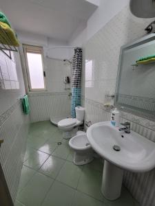 een witte badkamer met 2 toiletten en een wastafel bij Julia's Apartment in Golem Beach in Golem