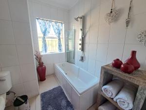 a white bathroom with a tub and a window at @ Home Bed & Breakfast in Brakpan