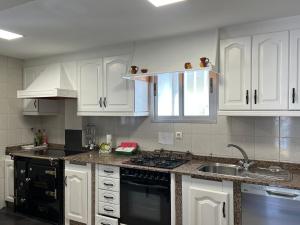 a kitchen with white cabinets and a black stove top oven at Casa do Cuco, Ribeira Sacra in Ourense