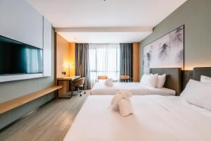 Habitación de hotel con 2 camas y TV de pantalla plana. en Laike Hotel en Bangkok