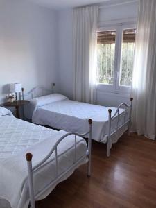 two beds in a white room with a window at Villa Eugenia in La Herradura