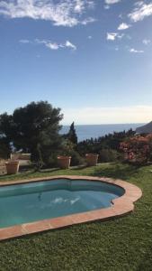 a swimming pool in the grass with the ocean in the background at Villa Eugenia in La Herradura