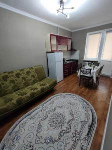 een woonkamer met een bank en een keuken met een tafel bij 2 комнатная Нурсат вдоль Аллеи in Simkent