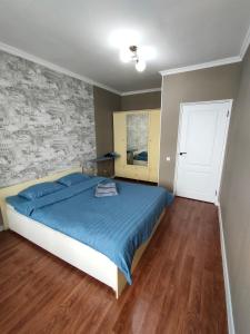 um quarto com uma cama com um edredão azul em 2 комнатная Нурсат вдоль Аллеи em Shymkent