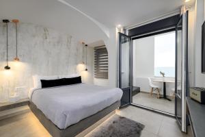 George & Joanna Suites Santorini في فيرا: غرفة نوم مع سرير أبيض كبير ومكتب