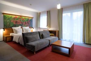 a living room with a couch and a bed at Hotel Szarlota - Kompleksowo na Kaszubach in Kościerzyna