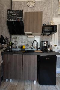 cocina con nevera negra y fregadero en Studio Malou, cuisine, salle d'eau, terrasse amenagée, en Olliergues