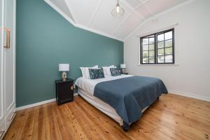 una camera da letto con un letto con pareti blu e una finestra di ‘The Black Pearl’ - Surfers Corner, Muizenburg a Città del Capo