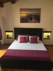 a bedroom with a large bed with purple sheets and pillows at Ortigia Deluxe S.A.L. in Syracuse