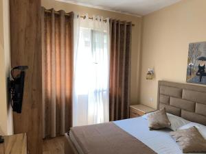 a bedroom with a bed and a window with curtains at Skampini Qerret Apartments in Golem