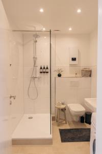 a white bathroom with a shower and a toilet at FeelsLikeHome - Traumhafte zentrumsnahe Wohnung mit Balkon&Parkplatz in Bochum