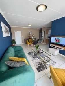 ein Wohnzimmer mit einem grünen Sofa und einem TV in der Unterkunft The Blyde 449 Reformity in Pretoria