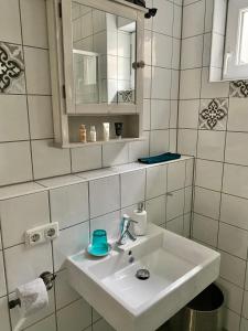 a white bathroom with a sink and a mirror at Sleek & modern exterior-entrance apartment in Nuremberg suburb in Heroldsberg