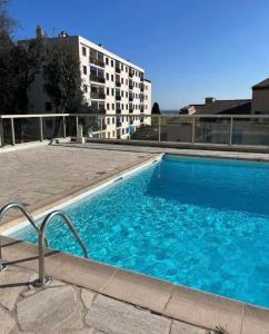 een groot blauw zwembad voor een gebouw bij Duplex apartment in a residence with swimming pool near Cannes in Le Cannet