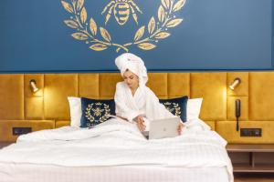 Eine Frau, die mit einem Laptop auf einem Bett sitzt. in der Unterkunft Queen Bee in Kiew