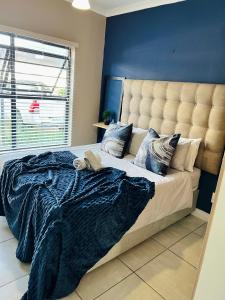 ein Schlafzimmer mit einem großen Bett mit blauer Wand in der Unterkunft The Blyde 449 Reformity in Pretoria