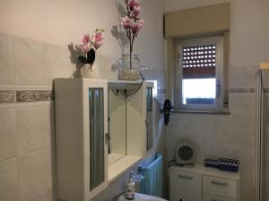 ein Badezimmer mit einem weißen Schrank mit Blumen darin in der Unterkunft Il mare a 100 M da casa con ampio giardino in Torregrotta