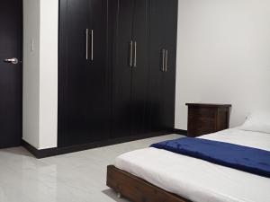 1 dormitorio con armarios negros y 1 cama con sábanas blancas en New comfortable house at Paipa close to everything great location, en Paipa