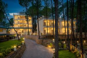 卡绍利Cassia Resort, Kasauli的一座白色的大建筑,树上灯火通明