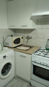 eine weiße Küche mit einer Spüle und einer Mikrowelle in der Unterkunft Elmarkos in Kolonia Chwaszczyńska
