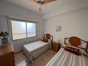 Apartamento ideal familias في Playa de Gandia: غرفة نوم بسريرين ونافذة