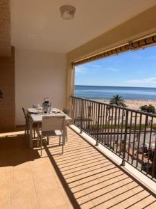 Apartamento ideal familias في Playa de Gandia: شرفة مع طاولة وإطلالة على الشاطئ