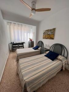 Apartamento ideal familias في Playa de Gandia: غرفة بثلاث اسرة وطاولة مع مروحة سقف