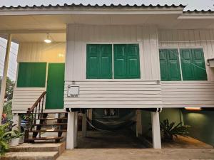 a house with green doors and a porch at Simple Home บ้าน-บะ-ดาย in Ban Long O