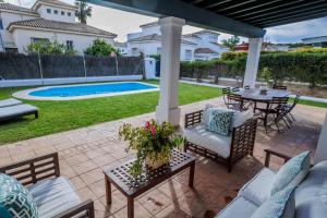 a patio with a table and chairs and a pool at GINVA - Villa Puerto Sherry in El Puerto de Santa María