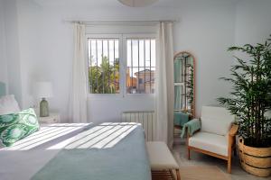 a bedroom with a bed and a chair and a window at GINVA - Villa Puerto Sherry in El Puerto de Santa María