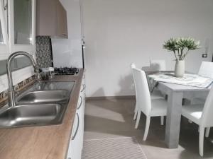 a kitchen with a sink and a table with white chairs at La casetta del Fico d'India in Marsala