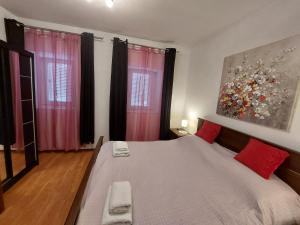 a bedroom with a large bed with red pillows at Apartman Rozmari in Lokve