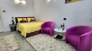 a bedroom with purple chairs and a bed and a table at Garsoniera centru vechi English park in Craiova