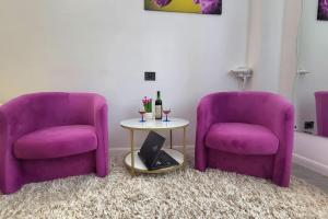 two purple chairs and a table with bottles of wine at Garsoniera centru vechi English park in Craiova
