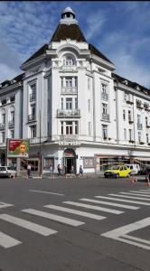 a large white building with a black roof on a street at Garsoniera centru vechi English park in Craiova