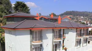 a row of white apartment buildings with black roofs at Two Seas Residence in Ooty