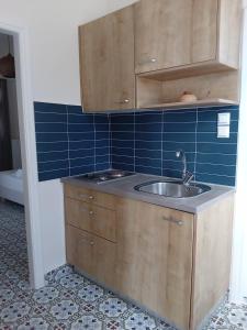 a kitchen with a sink and a blue tiled wall at Aerides Boutique Rooms in Vathi