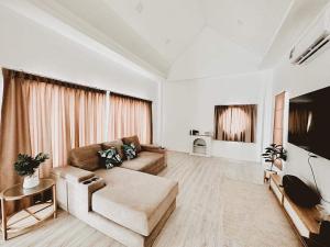 sala de estar con sofá y TV en First pool villa พลูวิลล่าโคราช, en Nakhon Ratchasima