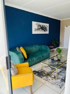 ein Wohnzimmer mit einem grünen Sofa und einer blauen Wand in der Unterkunft The Blyde 449 Reformity in Pretoria