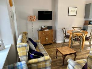 a living room with two couches and a table at Lottie’s Cottage, Rhynie, Aberdeenshire in Rhynie