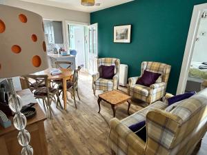 uma sala de estar com um sofá, cadeiras e uma mesa em Lottie’s Cottage, Rhynie, Aberdeenshire em Rhynie