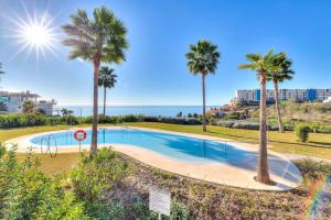 einen Pool mit Palmen und dem Meer in der Unterkunft Ocean & pool view 3-bedroom apt. in Málaga
