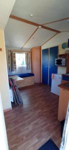 an empty room with wood floors and a room with a table at CAMPING LE BEL AIR- Mobil home le laurier in Limogne-en-Quercy +5 photos
