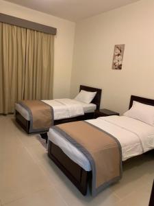 AL MARJAN FURNISHED APARTMENTS في عجمان: سريرين في غرفة الفندق مع تنورات