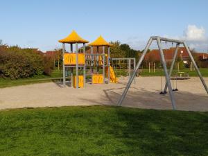 a playground with a swing set in a park at Sommerhaus Nessmersiel in Neßmersiel