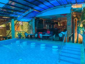 a swimming pool with chairs and tables and a bar at Mabini Hotel in Mambajao
