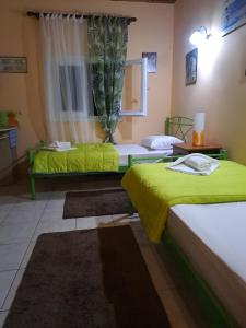 Habitación con 2 camas con sábanas verdes y ventana en Spiros Corfu Apartment, en Kanálion