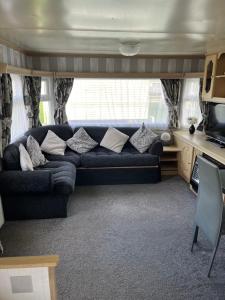 a living room with a couch and a tv at Colemans Caravans Golden Anchor Caravan Park in Chapel Saint Leonards