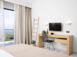a bedroom with a desk and a television on a wall at Sunrise Village Beach Hotel in Kalamaki Messinia
