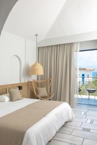 a bedroom with a bed and a chair and a window at Sunrise Village Beach Hotel in Kalamaki Messinia